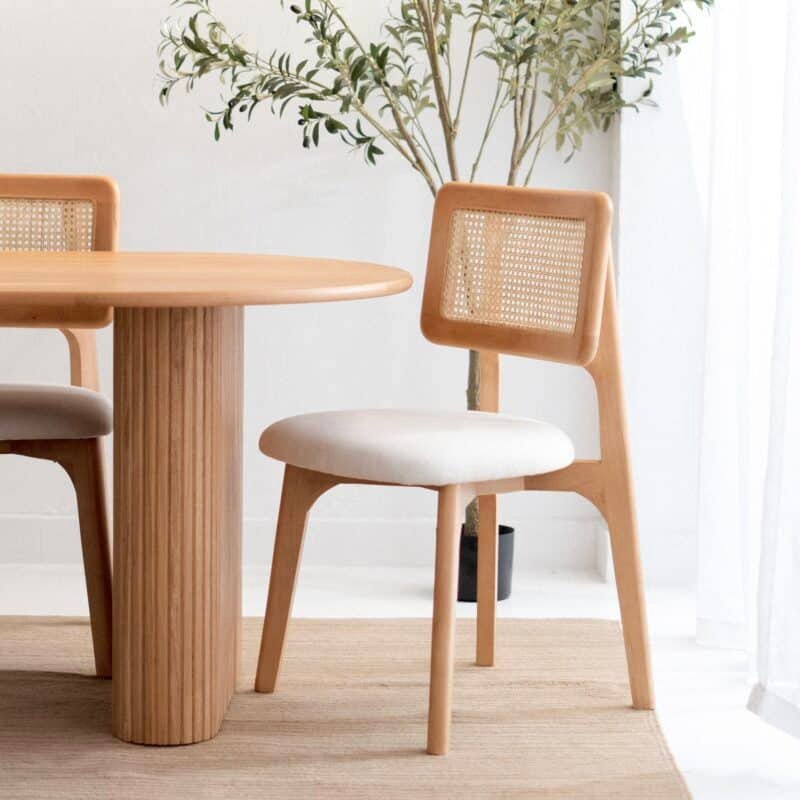 Wooden dining chair with cane back beside a round wooden table