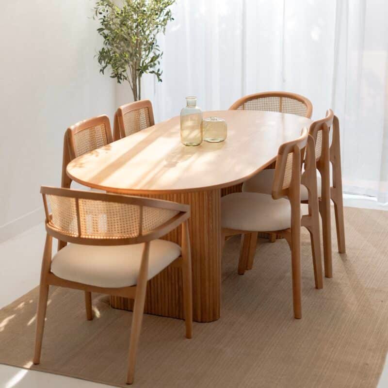 Oval wooden dining table with matching chairs in a styled dining room