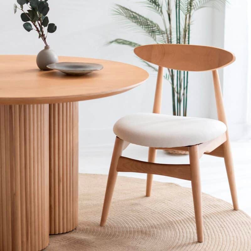 Wooden dining chair with upholstered seat beside a round wooden table